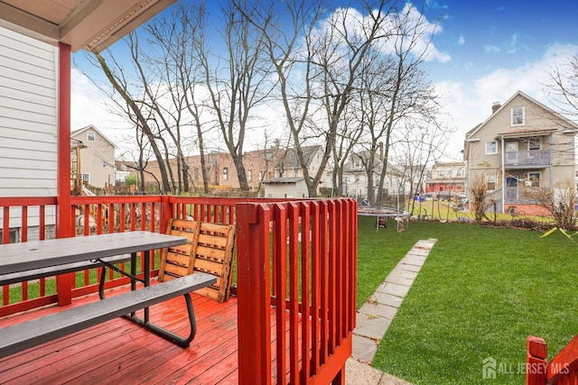 wooden terrace with a trampoline, a residential view, a yard, and fence