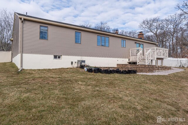 back of property with a wooden deck and a yard