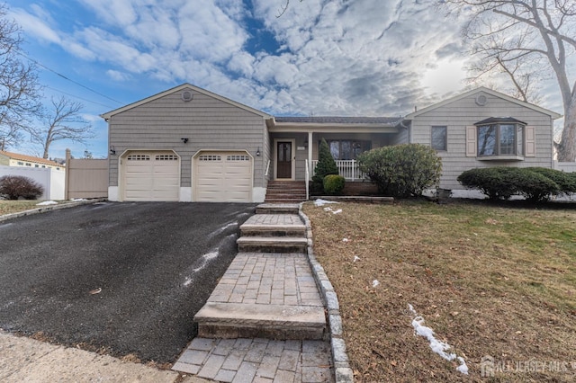 single story home featuring aphalt driveway, covered porch, fence, a garage, and a front lawn