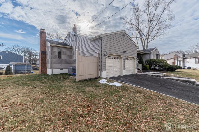 view of side of home featuring central AC unit, a yard, and a garage