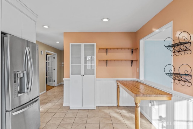 interior space with light tile patterned flooring and stainless steel refrigerator with ice dispenser