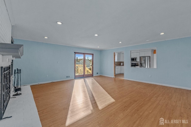 unfurnished living room featuring ornamental molding, a brick fireplace, and light hardwood / wood-style floors