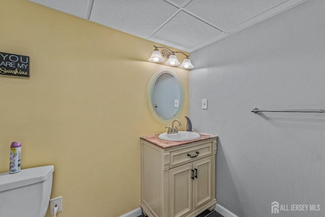 bathroom featuring vanity, toilet, and a drop ceiling