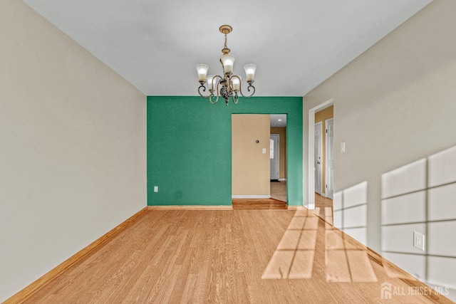 spare room with a chandelier and hardwood / wood-style floors