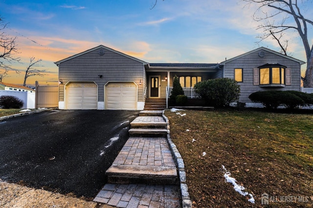 ranch-style house featuring driveway, a porch, an attached garage, and fence