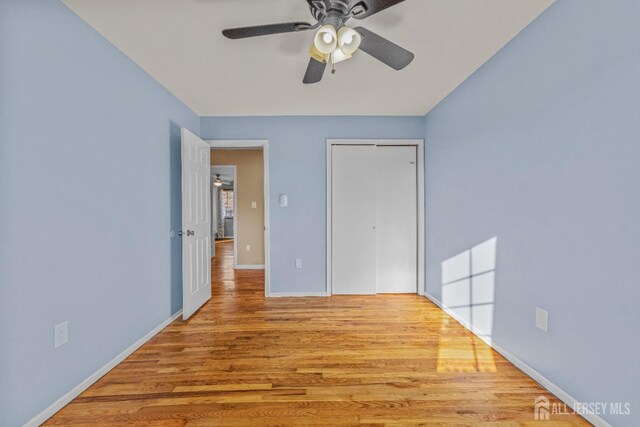 unfurnished bedroom with light hardwood / wood-style flooring, a closet, and ceiling fan