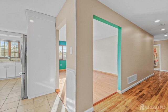 hall with plenty of natural light, sink, and light wood-type flooring