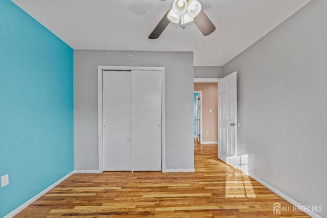 unfurnished bedroom with ceiling fan, light wood-type flooring, and a closet