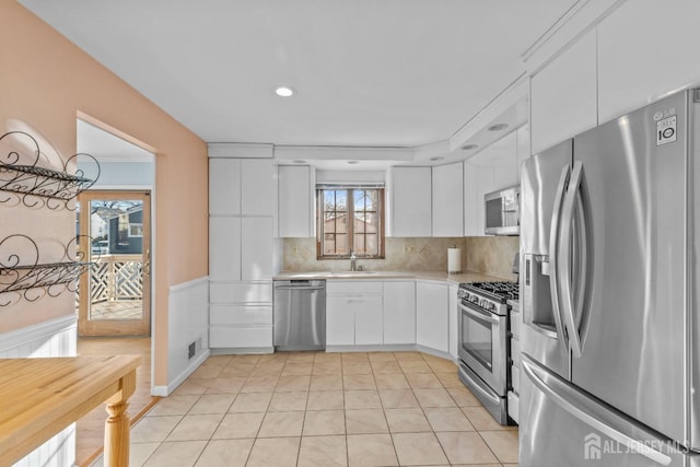 kitchen featuring sink, white cabinetry, tasteful backsplash, light tile patterned floors, and stainless steel appliances