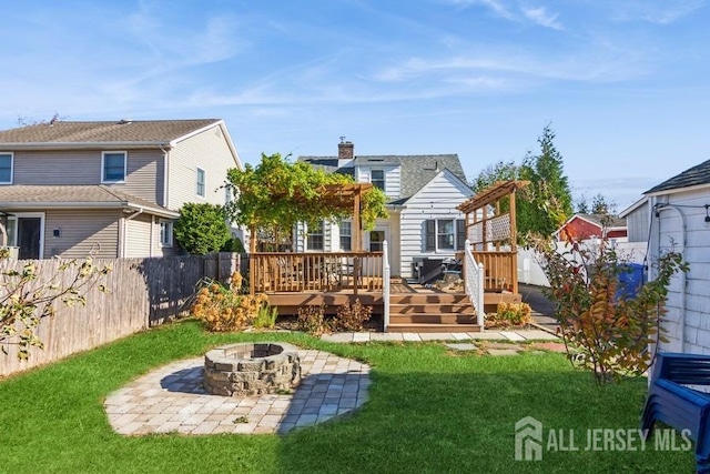 rear view of property featuring a wooden deck, an outdoor fire pit, and a yard