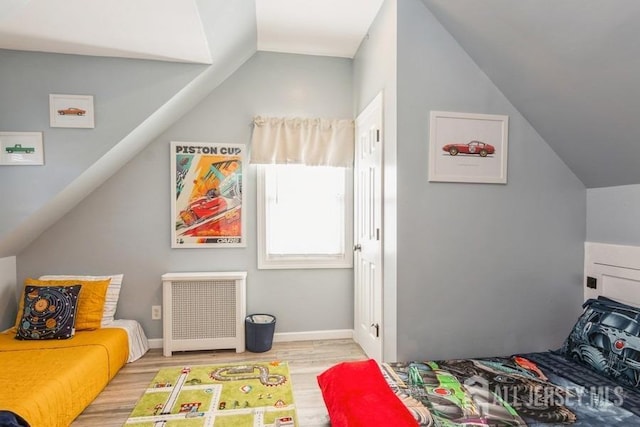 recreation room featuring radiator heating unit, light hardwood / wood-style flooring, and lofted ceiling