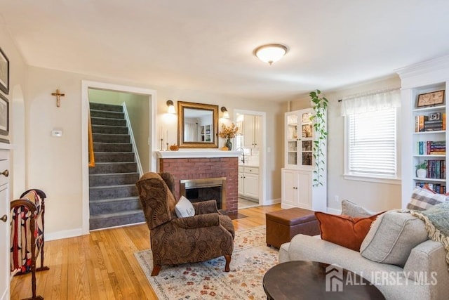 living room featuring a brick fireplace and light hardwood / wood-style floors