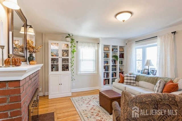 living room with light wood-type flooring, a brick fireplace, and a healthy amount of sunlight