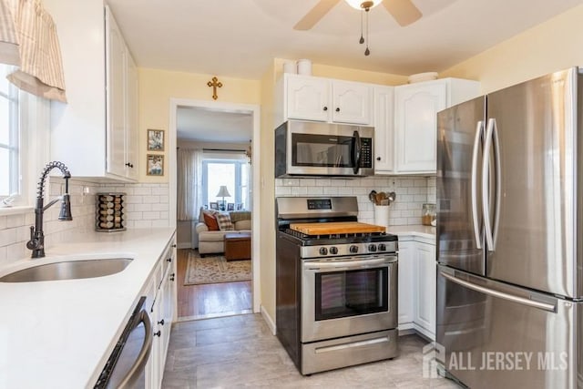 kitchen featuring sink, backsplash, white cabinets, and appliances with stainless steel finishes