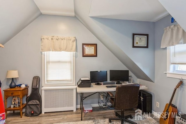 home office with light wood-type flooring, vaulted ceiling, and radiator heating unit