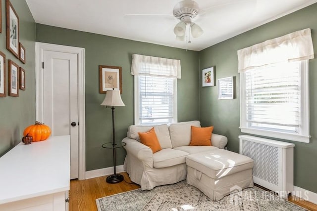 living area with radiator heating unit, light hardwood / wood-style flooring, and ceiling fan