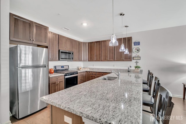 30 Grabowski Dr, Sayreville, NJ 08859 - kitchen featuring stainless steel appliances, a peninsula, a kitchen breakfast bar, light stone countertops, and hanging light fixtures