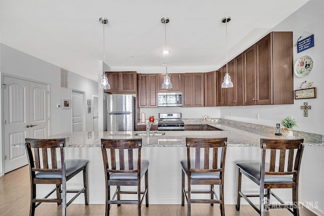 30 Grabowski Dr, Sayreville, NJ 08859 - kitchen featuring appliances with stainless steel finishes, a peninsula, light wood finished floors, decorative light fixtures, and light stone countertops