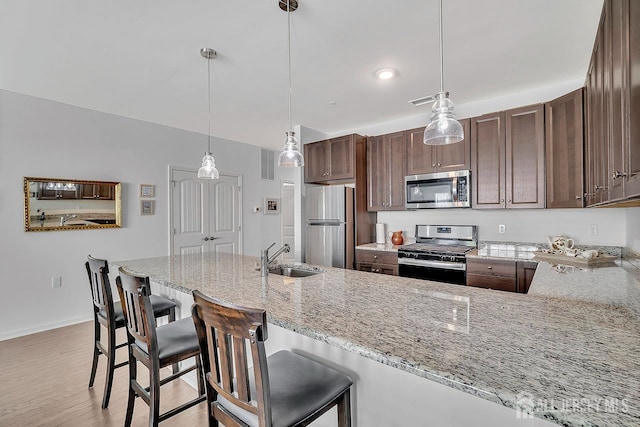 30 Grabowski Dr, Sayreville, NJ 08859 - kitchen with stainless steel appliances, light stone countertops, light wood-type flooring, pendant lighting, and a kitchen bar