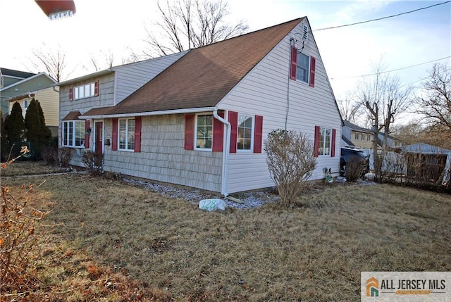 view of property exterior with a yard, a shingled roof, and fence