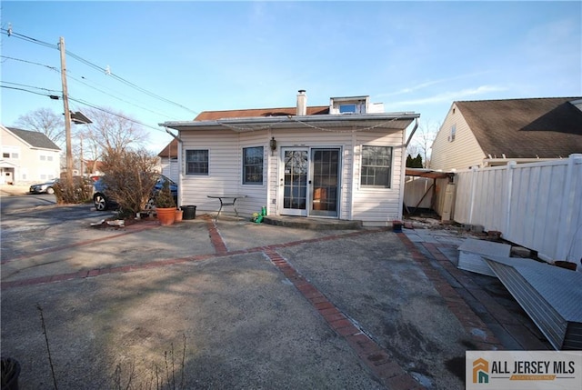 back of house with a patio, a chimney, and fence