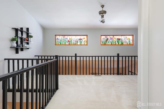 hall featuring an upstairs landing and carpet