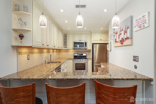 kitchen with stainless steel appliances, cream cabinets, a sink, backsplash, and light stone counters
