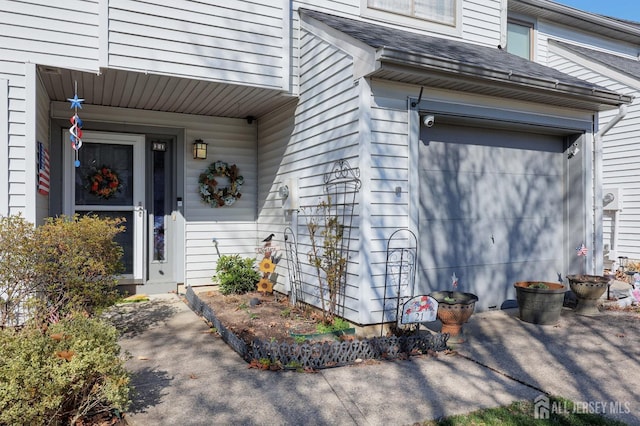 view of exterior entry with a shingled roof and a garage
