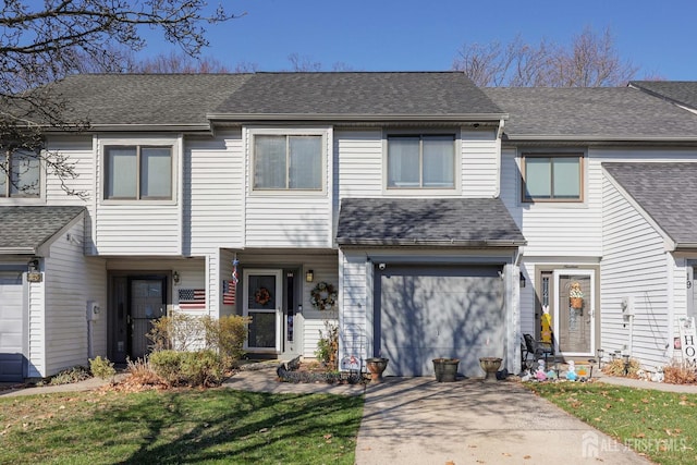 multi unit property with concrete driveway, an attached garage, roof with shingles, and a front lawn