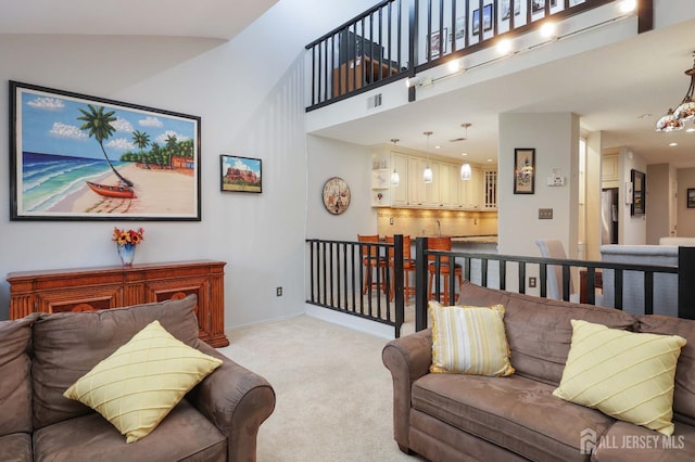 living area featuring light carpet, a high ceiling, and baseboards
