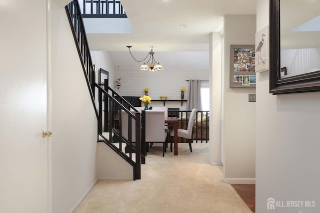 corridor featuring stairway, baseboards, a chandelier, and carpet flooring