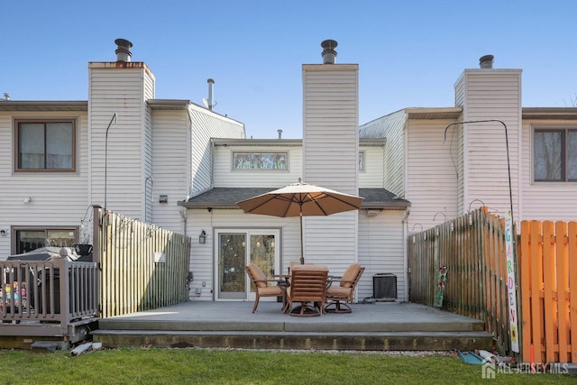 back of property featuring a chimney, a wooden deck, fence, and central AC