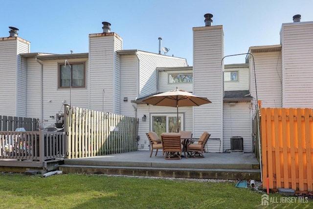 rear view of property featuring a chimney, a deck, and central AC