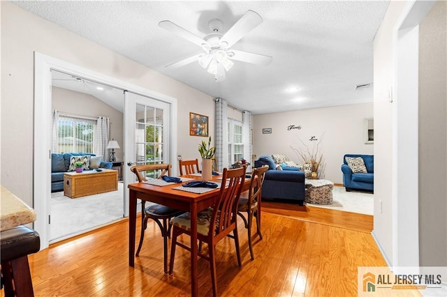 dining space featuring light wood-style floors, a ceiling fan, and a textured ceiling