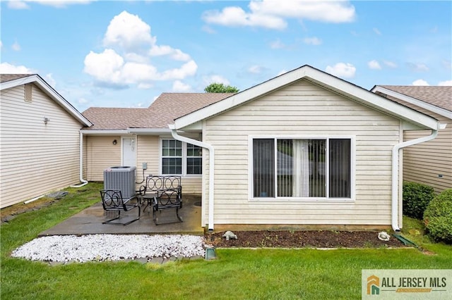 rear view of house with central AC, a patio, a yard, and a shingled roof