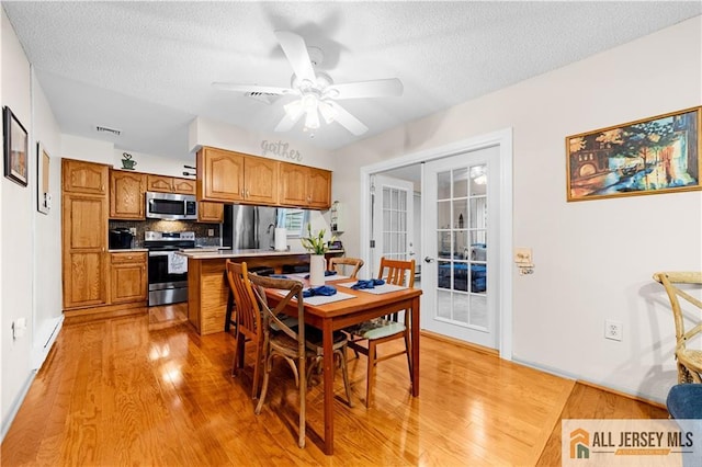 dining room featuring french doors, light wood finished floors, ceiling fan, and a textured ceiling