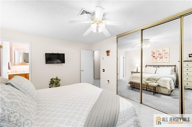 bedroom with a closet, light colored carpet, a ceiling fan, connected bathroom, and a textured ceiling