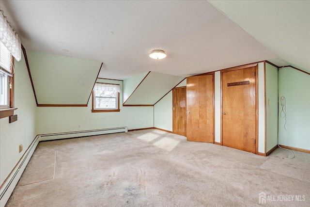 additional living space featuring lofted ceiling, light colored carpet, and baseboard heating