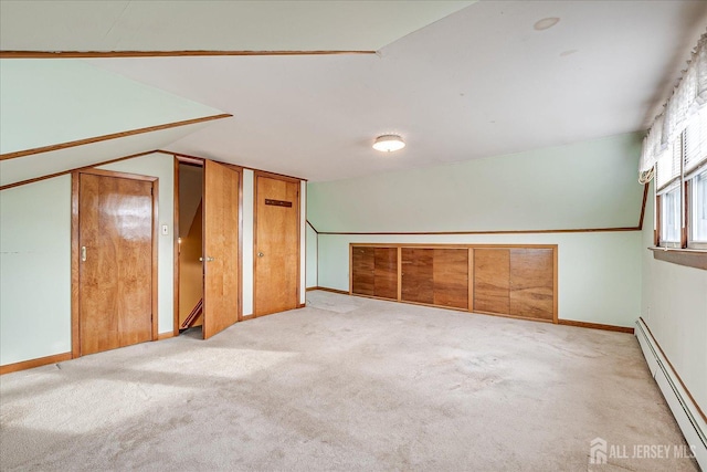 additional living space with lofted ceiling, a baseboard heating unit, and light colored carpet