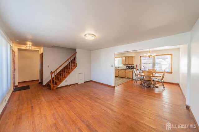 unfurnished living room featuring sink, light hardwood / wood-style flooring, and a notable chandelier