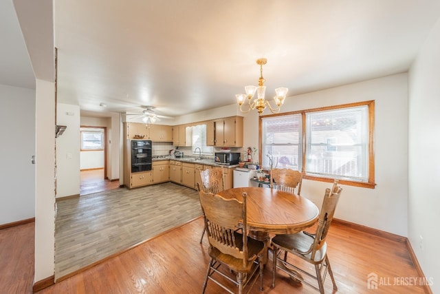 dining area with ceiling fan with notable chandelier, sink, and light hardwood / wood-style flooring