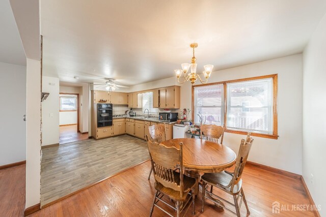 dining area with light wood-type flooring, sink, and ceiling fan with notable chandelier