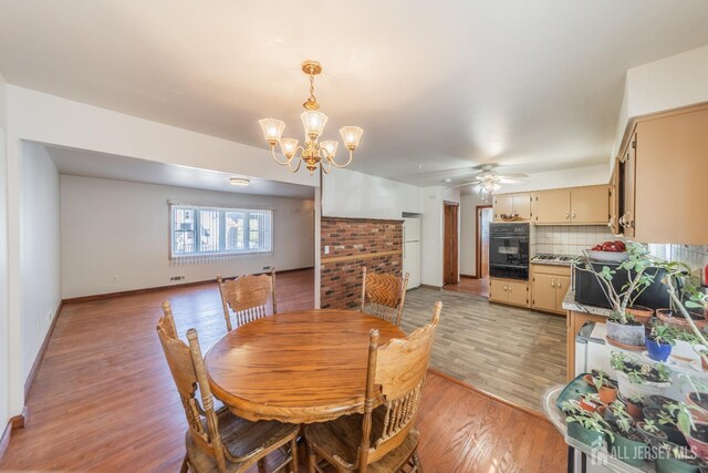 dining space with ceiling fan with notable chandelier and light hardwood / wood-style floors