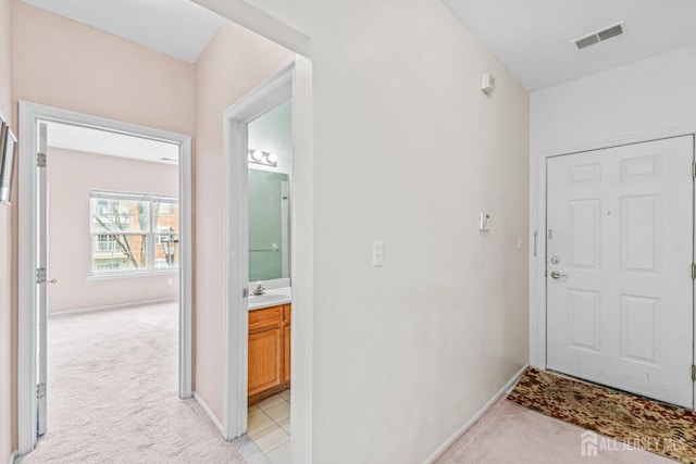 interior space with a sink, baseboards, visible vents, and light carpet