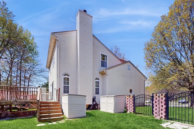 back of house with a lawn, a chimney, fence, and a deck