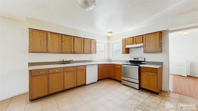 kitchen with under cabinet range hood, light countertops, dishwasher, stainless steel range with gas stovetop, and brown cabinetry