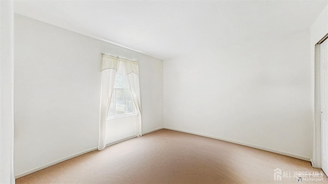 unfurnished room featuring baseboards and light colored carpet