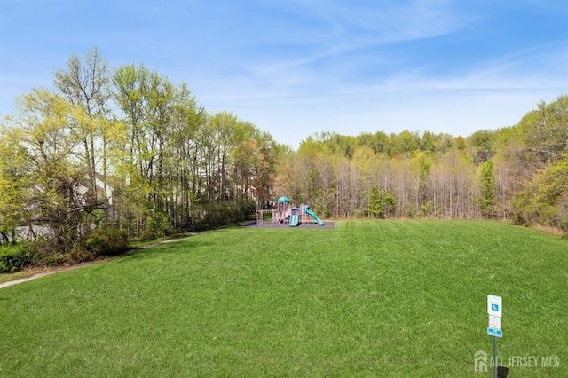 view of yard featuring playground community and a view of trees