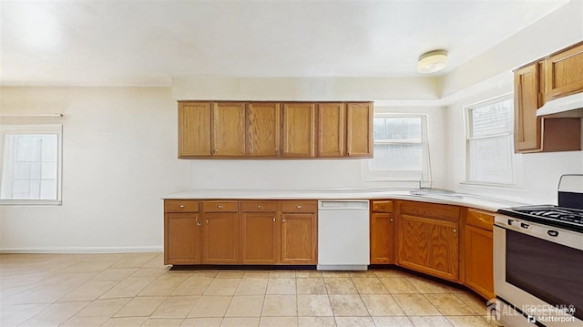 kitchen featuring white dishwasher, light countertops, stainless steel range, and brown cabinets