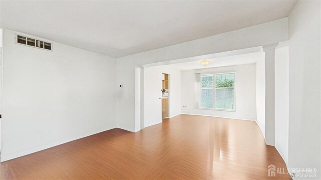 spare room featuring baseboards, wood finished floors, and visible vents